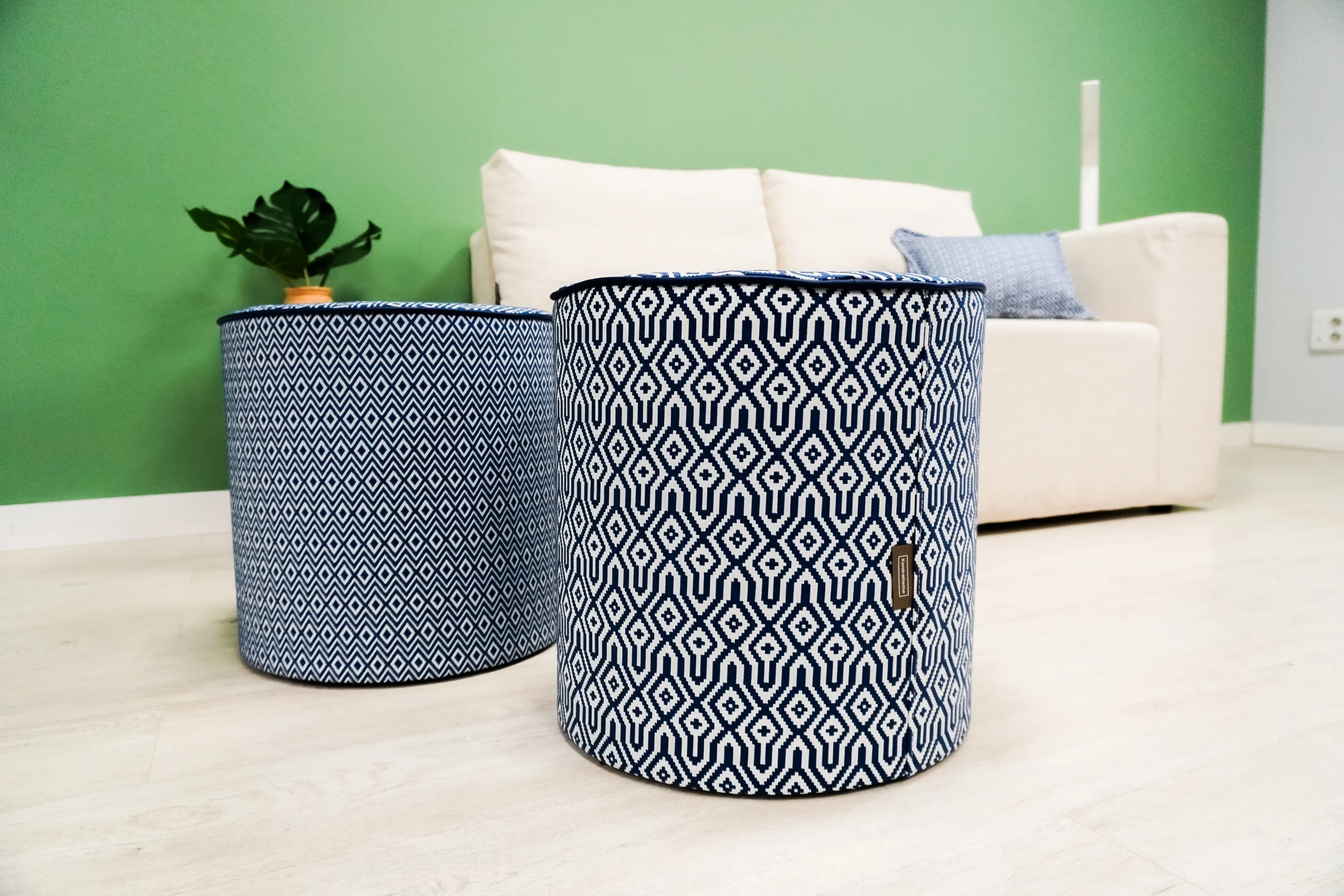 Puf redondo cilíndricos tapizados en azul junto a sofá crema.